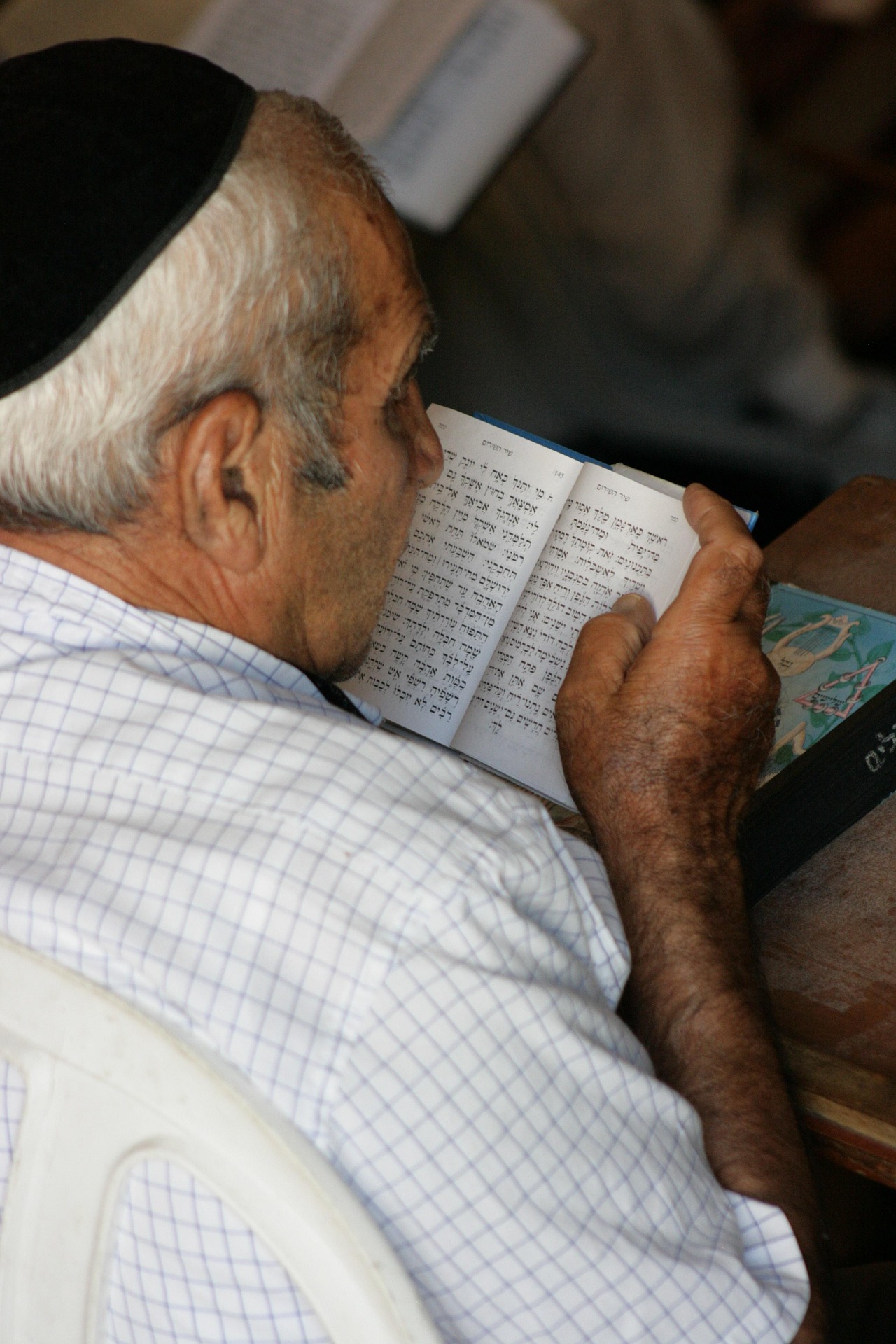 Close-up of a hand reaching for a Torah book on a bookshelf, symbolizing Jewish culture.